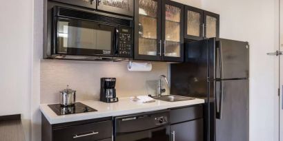 Sonesta Simply Suites Arlington guest room kitchen area, including fridge-freezer, oven, hob, and microwave.