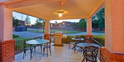 The hotel’s gazebo provides outdoor tables and chairs under cover, with greenery nearby and a barbecue.