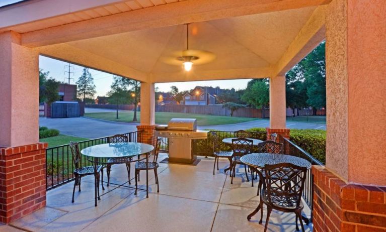 The hotel’s gazebo provides outdoor tables and chairs under cover, with greenery nearby and a barbecue.