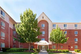 Sonesta Simply Suites Arlington’s exterior has clear signage, beautiful lawns, and towering trees.