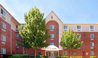 Sonesta Simply Suites Arlington’s exterior has clear signage, beautiful lawns, and towering trees.