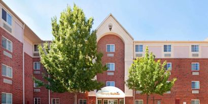 Sonesta Simply Suites Arlington’s exterior has clear signage, beautiful lawns, and towering trees.