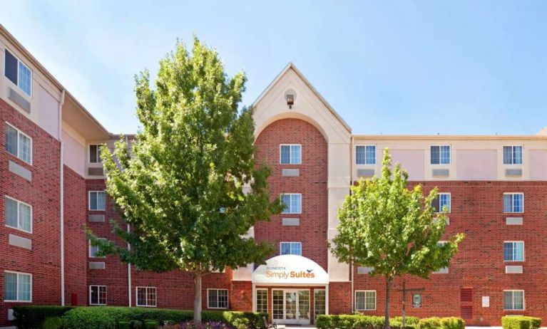 Sonesta Simply Suites Arlington’s exterior has clear signage, beautiful lawns, and towering trees.