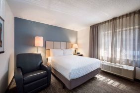 Double bed guest room in Sonesta Simply Suites Nashville Brentwood, featuring armchair, bedside lamp, and window.