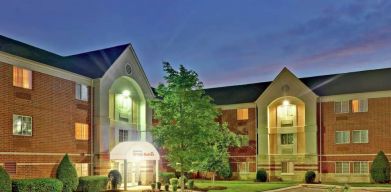 Sonesta Simply Suites Nashville Brentwood’s exterior is brightly lit and has well-tended lawns, bushes, and trees.