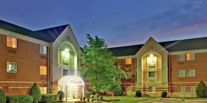 Sonesta Simply Suites Nashville Brentwood’s exterior is brightly lit and has well-tended lawns, bushes, and trees.