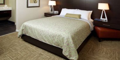 Sonesta ES Suites San Jose Airport double bed guest room, including bedside lamps and an ensuite bathroom.