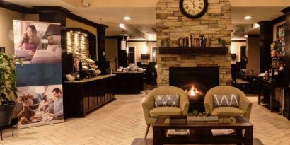 The hotel’s lobby has comfortable seating, a coffee table, reading material, and a cozy fireplace.