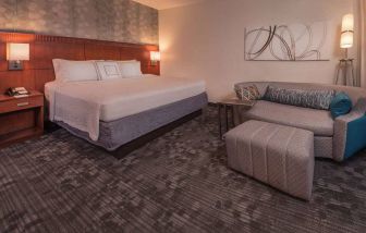 Double bed guest room in Sonesta Select Arlington Rosslyn, furnished with wall art, sofa, and coffee table.