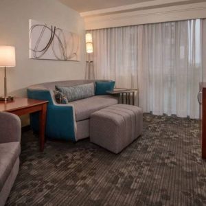 Sonesta Select Arlington Rosslyn guest room lounge with sofa, armchair, window, and TV.