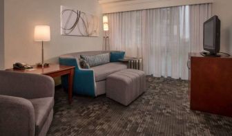 Sonesta Select Arlington Rosslyn guest room lounge with sofa, armchair, window, and TV.