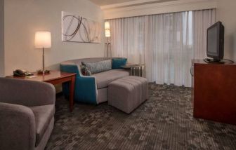 Sonesta Select Arlington Rosslyn guest room lounge with sofa, armchair, window, and TV.