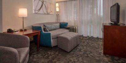 Sonesta Select Arlington Rosslyn guest room lounge with sofa, armchair, window, and TV.