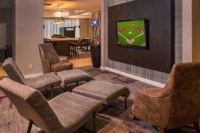 Sonesta Select Arlington Rosslyn’s lobby features a large, wall-mounted TV, with armchairs and reclined seating with footstools.