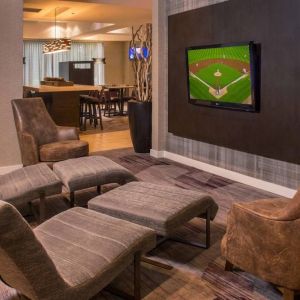 Sonesta Select Arlington Rosslyn’s lobby features a large, wall-mounted TV, with armchairs and reclined seating with footstools.