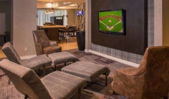 Sonesta Select Arlington Rosslyn’s lobby features a large, wall-mounted TV, with armchairs and reclined seating with footstools.