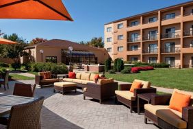 The hotel terrace is furnished with shaded tables and chairs, plus armchairs and sofa seating with adjacent coffee tables.