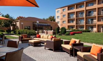 The hotel terrace is furnished with shaded tables and chairs, plus armchairs and sofa seating with adjacent coffee tables.