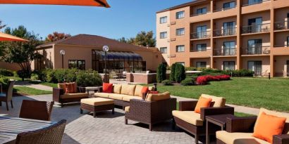 The hotel terrace is furnished with shaded tables and chairs, plus armchairs and sofa seating with adjacent coffee tables.