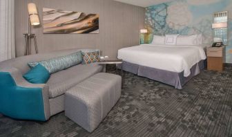 Sonesta Select Allentown Bethlehem Airport double bed guest room, with art on the wall, sofa, and long footstool.