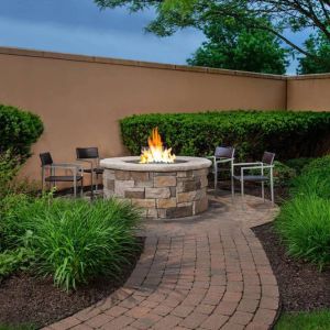 The hotel’s fire pit has chairs and abundant greenery around it.