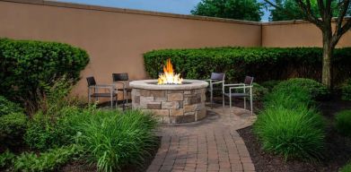 The hotel’s fire pit has chairs and abundant greenery around it.