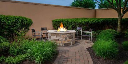 The hotel’s fire pit has chairs and abundant greenery around it.