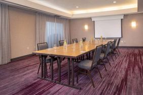 Sonesta Select Allentown Bethlehem Airport meeting room, including long wooden table, projector screen, seating for eight, and window.