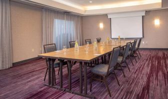 Sonesta Select Allentown Bethlehem Airport meeting room, including long wooden table, projector screen, seating for eight, and window.