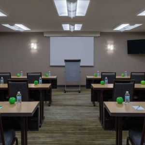 Hotel meeting room, with tables arranged in a classroom format, facing a lectern, TV, and whiteboard.