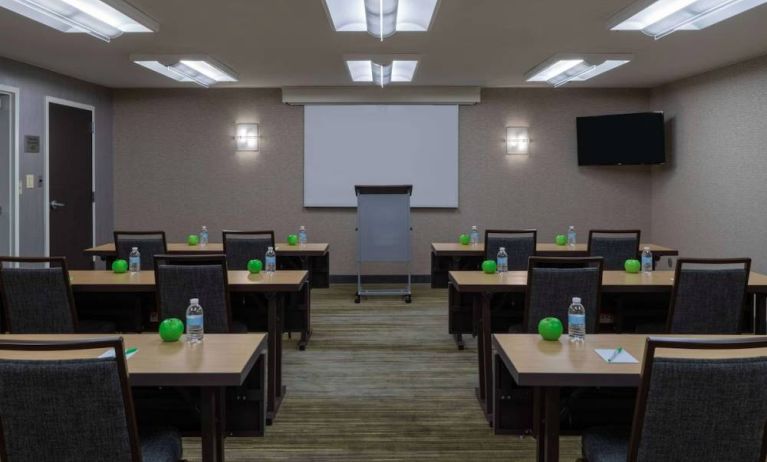 Hotel meeting room, with tables arranged in a classroom format, facing a lectern, TV, and whiteboard.