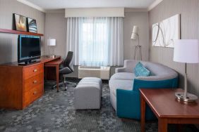 Sonesta Select Boston Lowell Chelmsford guest room lounge, furnished with sofa, chair, and TV.