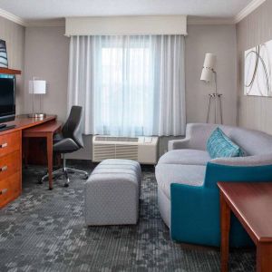 Sonesta Select Boston Lowell Chelmsford guest room lounge, furnished with sofa, chair, and TV.