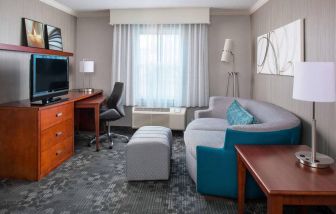 Sonesta Select Boston Lowell Chelmsford guest room lounge, furnished with sofa, chair, and TV.