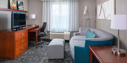 Sonesta Select Boston Lowell Chelmsford guest room lounge, furnished with sofa, chair, and TV.