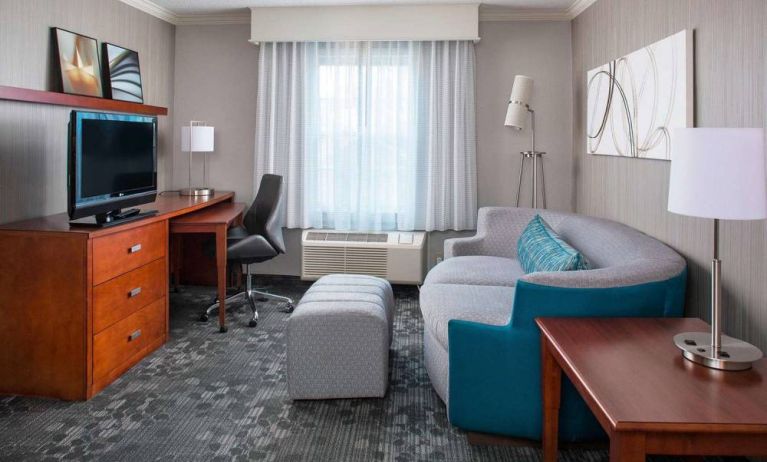 Sonesta Select Boston Lowell Chelmsford guest room lounge, furnished with sofa, chair, and TV.