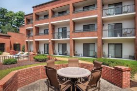 The hotel patio is close to the rooms, and has a circular table surrounded by a quintet of chairs.