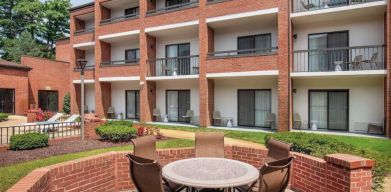 The hotel patio is close to the rooms, and has a circular table surrounded by a quintet of chairs.