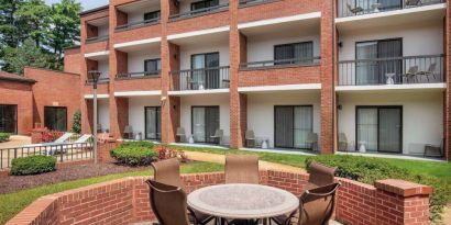 The hotel patio is close to the rooms, and has a circular table surrounded by a quintet of chairs.