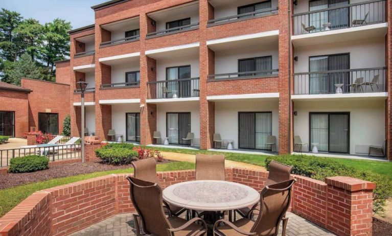 The hotel patio is close to the rooms, and has a circular table surrounded by a quintet of chairs.