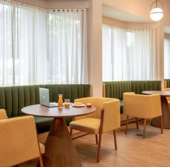 The hotel’s breakfast area has comfy seating, stylish tables, and large windows.