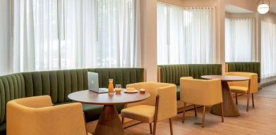 The hotel’s breakfast area has comfy seating, stylish tables, and large windows.