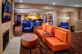 The hotel’s lobby lounge is furnished with armchair and sofa seating, coffee tables, a large television, and a fireplace.