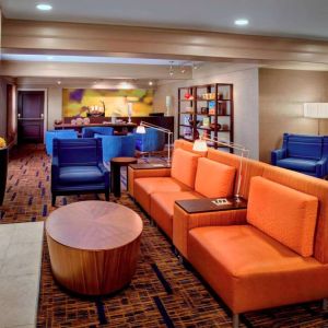 The hotel’s lobby lounge is furnished with armchair and sofa seating, coffee tables, a large television, and a fireplace.