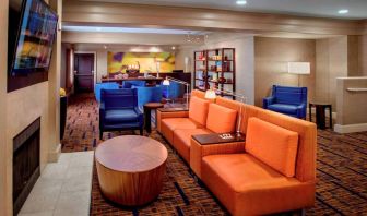 The hotel’s lobby lounge is furnished with armchair and sofa seating, coffee tables, a large television, and a fireplace.