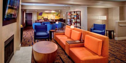 The hotel’s lobby lounge is furnished with armchair and sofa seating, coffee tables, a large television, and a fireplace.