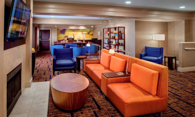 The hotel’s lobby lounge is furnished with armchair and sofa seating, coffee tables, a large television, and a fireplace.