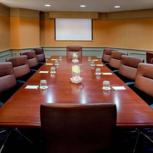 Sonesta Select Boston Danvers meeting room, with ten swivel chairs around a long table, and a projector screen.