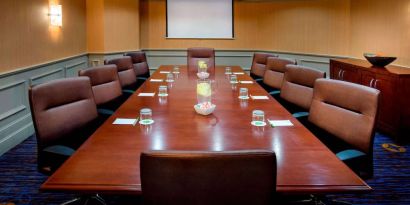 Sonesta Select Boston Danvers meeting room, with ten swivel chairs around a long table, and a projector screen.