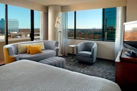 Sonesta Select Atlanta Cumberland Galleria double bed guest room, featuring sofa, chair, windows, and TV.